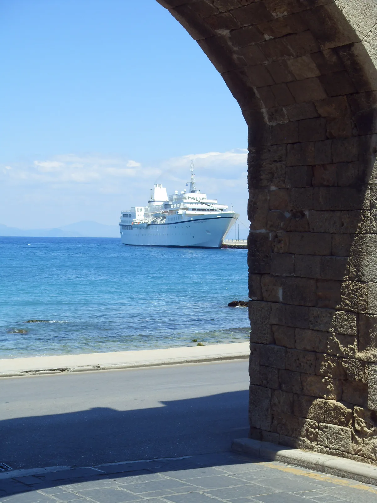 Kreuzfahrtschiff vor Rhodos, durch einen alten Steinbogen gesehen